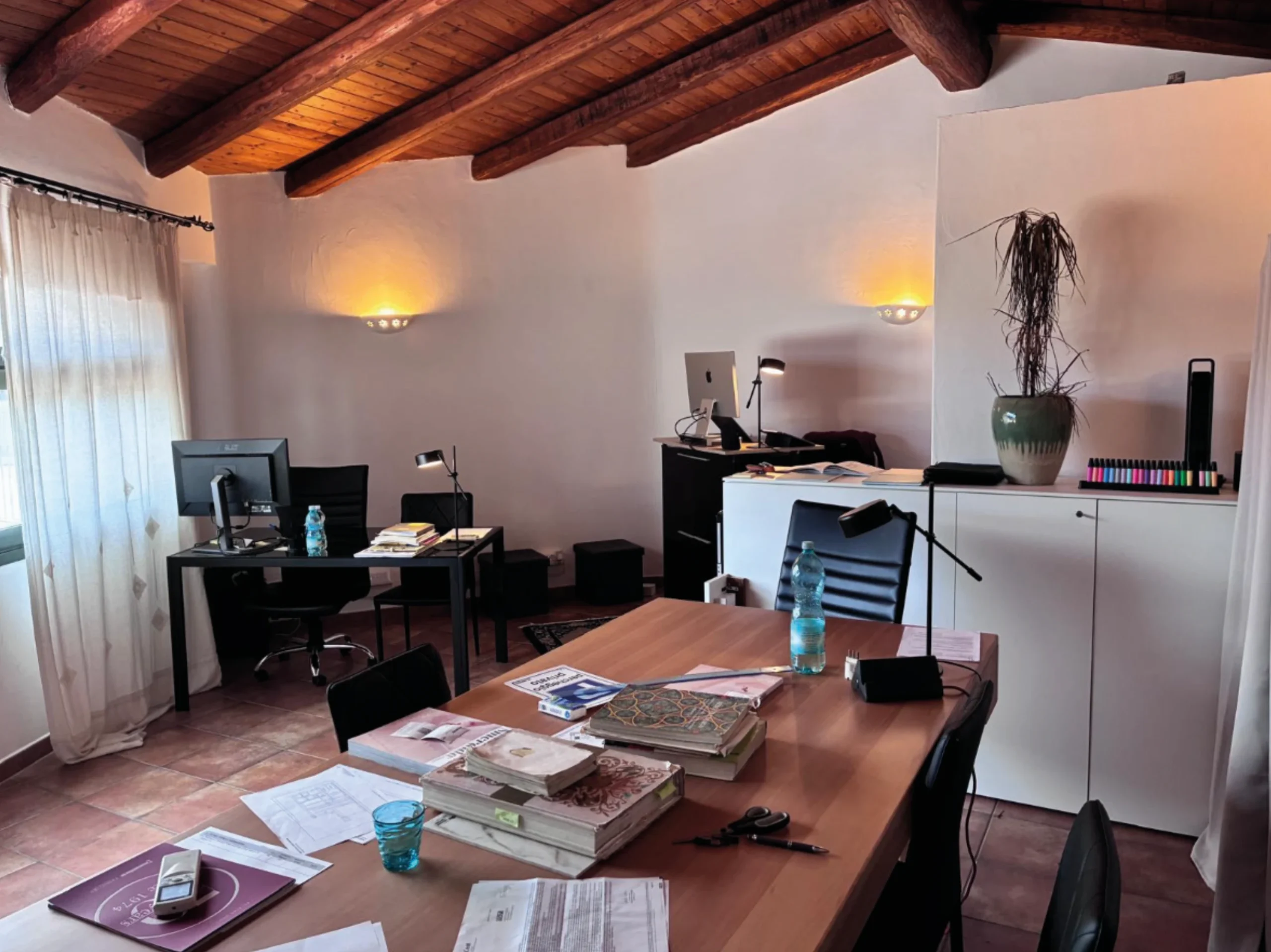 interno dello studio di progettazione Scetti, con scrivanie, computer, libri e altro materiale cartaceo